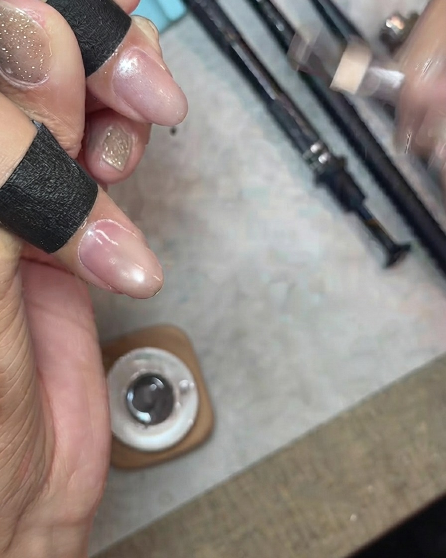 Applying a layer of sheer, fine shimmer cat-eye gel over a fingernail.