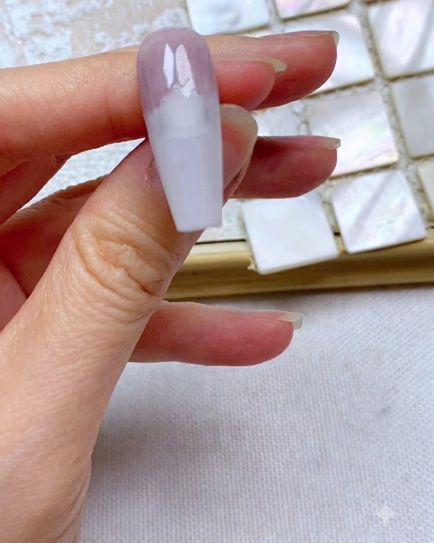 A nail showing a perfectly straight and neat edge of grey-purple gel applied to the top one-third.