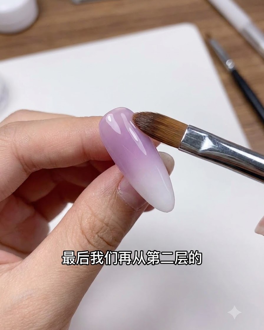 A clean nail brush gently feathering the transition line on a purple and white gradient nail.
