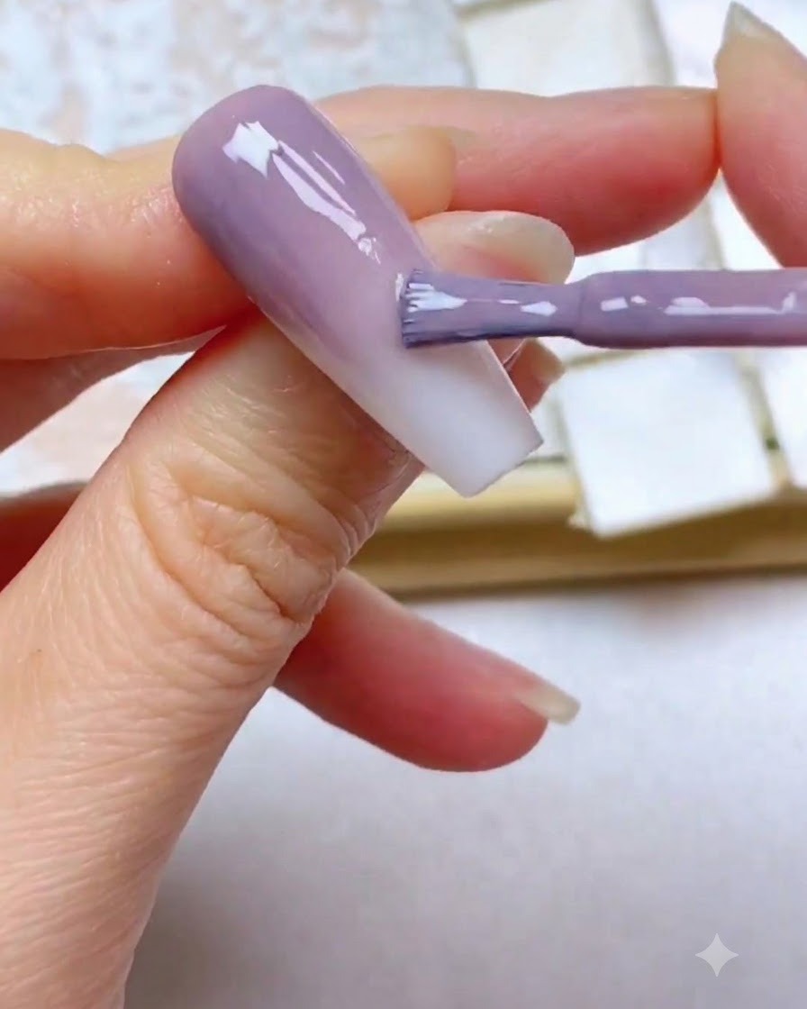 A gel brush applying a third layer of purple color near the top edge of the nail.