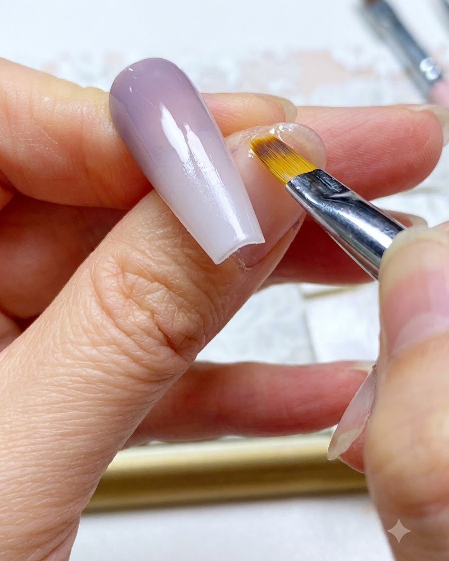 A nail brush doing a final touch-up sweep along the blended color section of the nail.