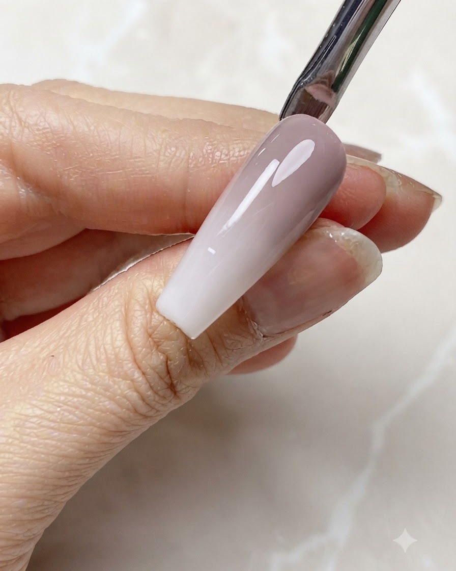 Translucent milky white gel being applied to the tip of a gradient nail.