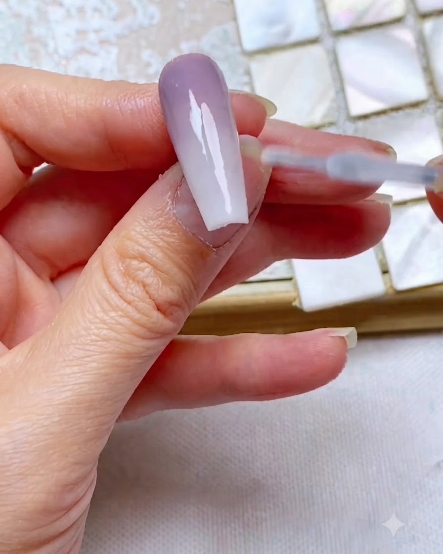 A top coat brush gliding smoothly over a finished two-tone gradient nail to seal and add gloss.