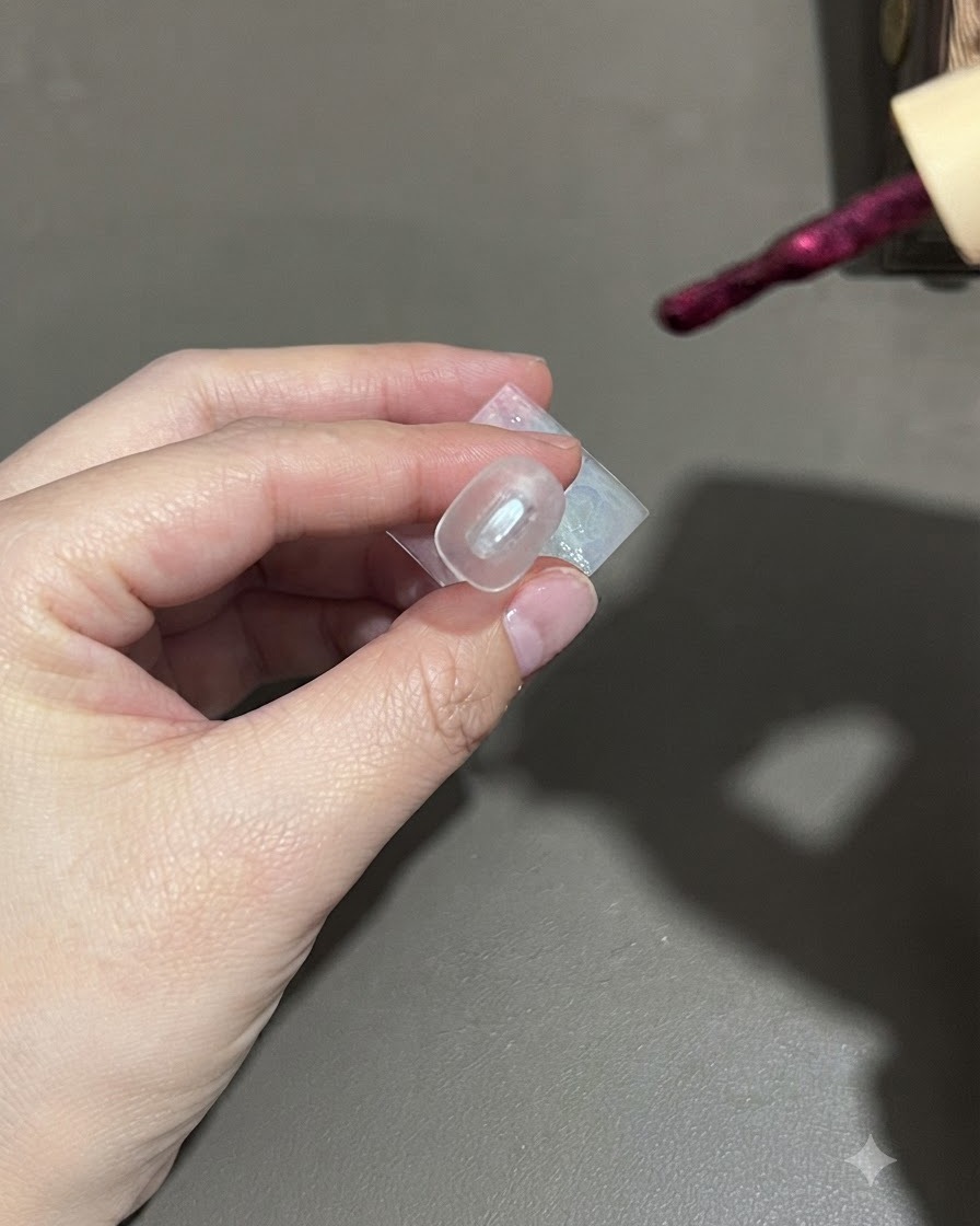A brush applying dark purple cat-eye gel polish onto a nail.