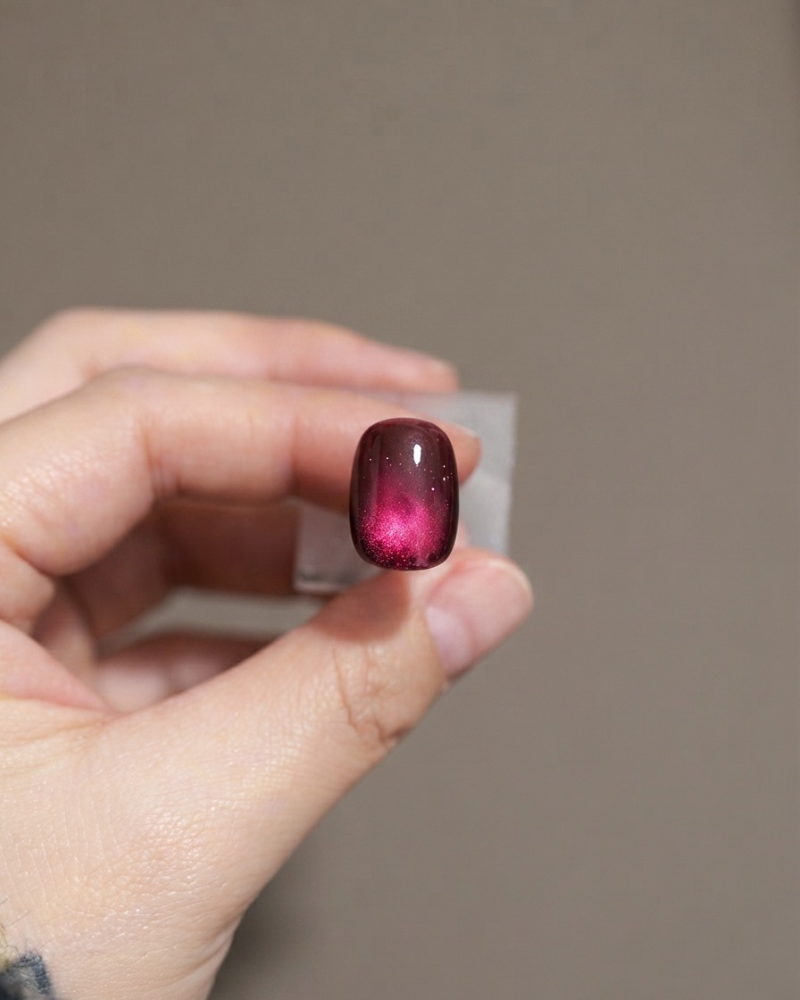 A nail showing a second layer of dark purple cat-eye gel polish.