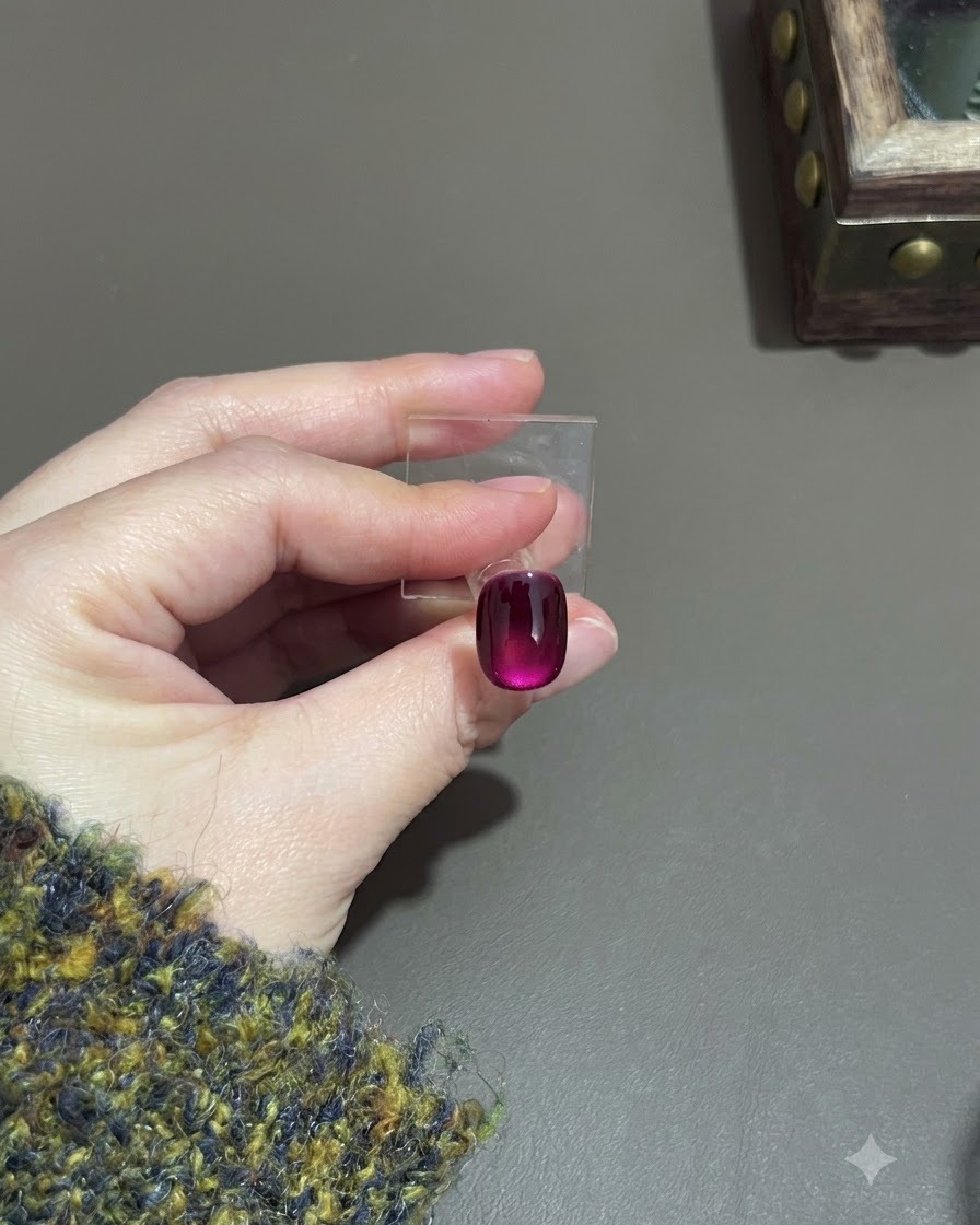 A cured purple cat-eye nail showing a deep gradient effect on a display stand.