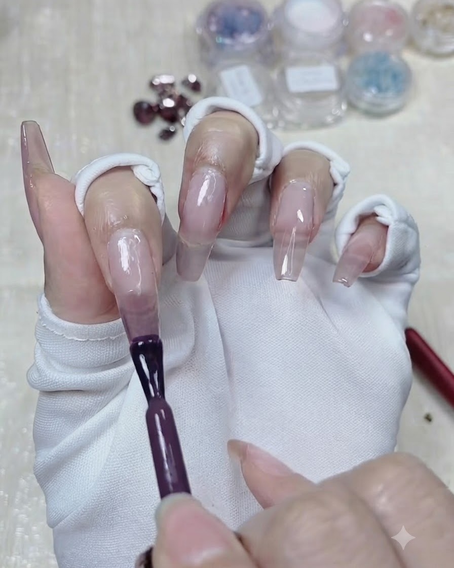 A brush applying a second, deeper layer of taro purple gel to the top half of the nail.