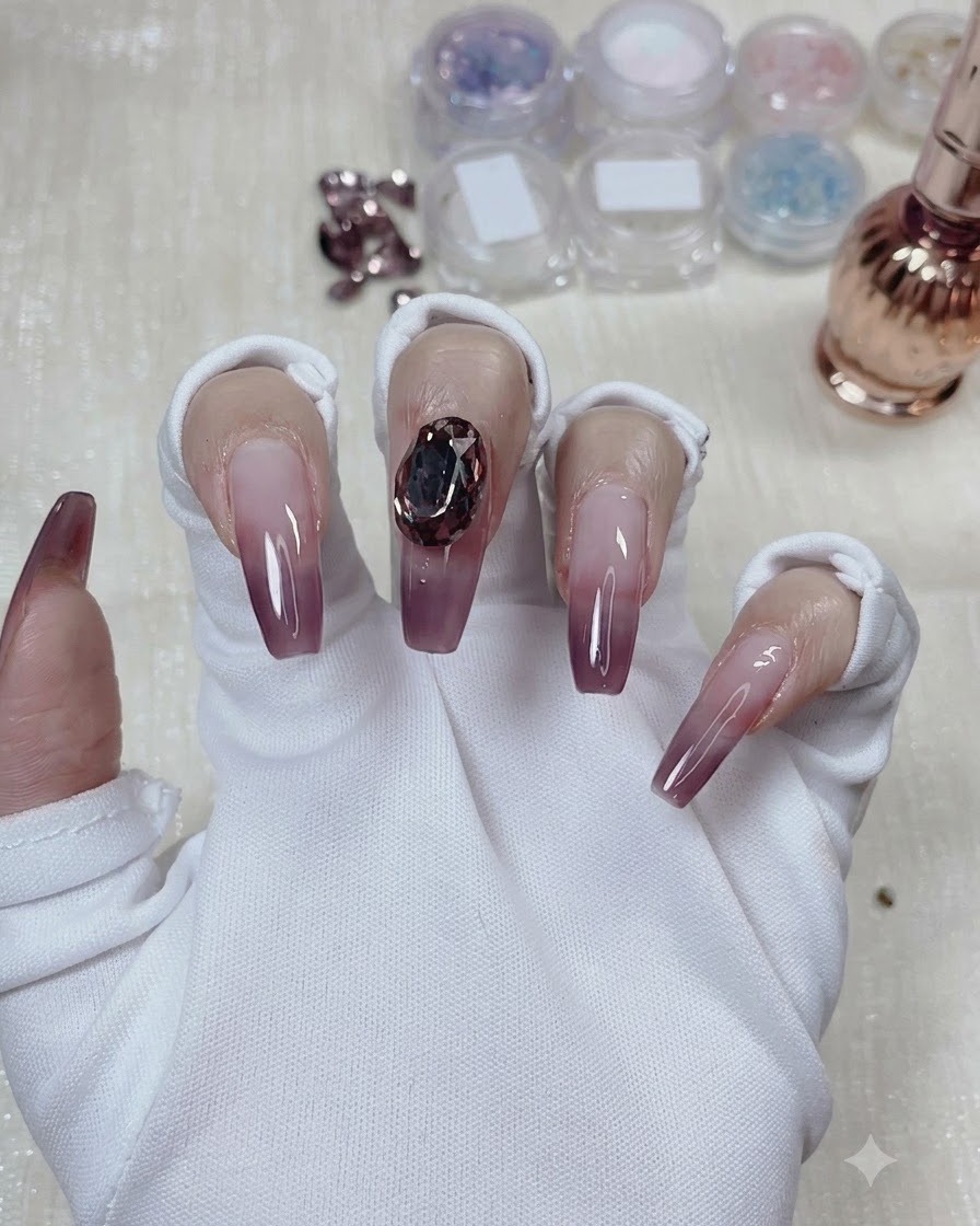 A large dove egg-shaped crystal gem securely placed in the center of the taro purple gradient nail.