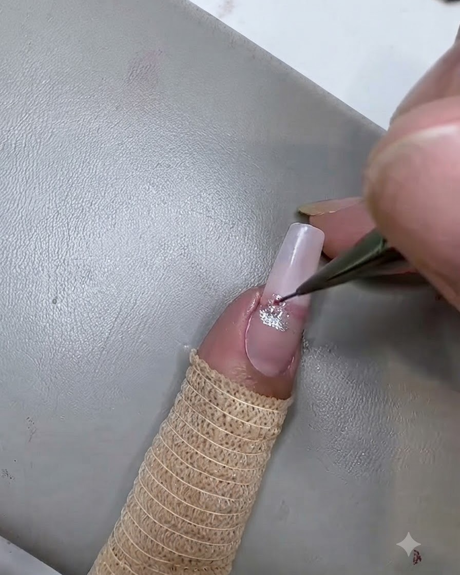 A fine liner brush applying a second pink cat eye gel stripe below the silver stripe on the nail.