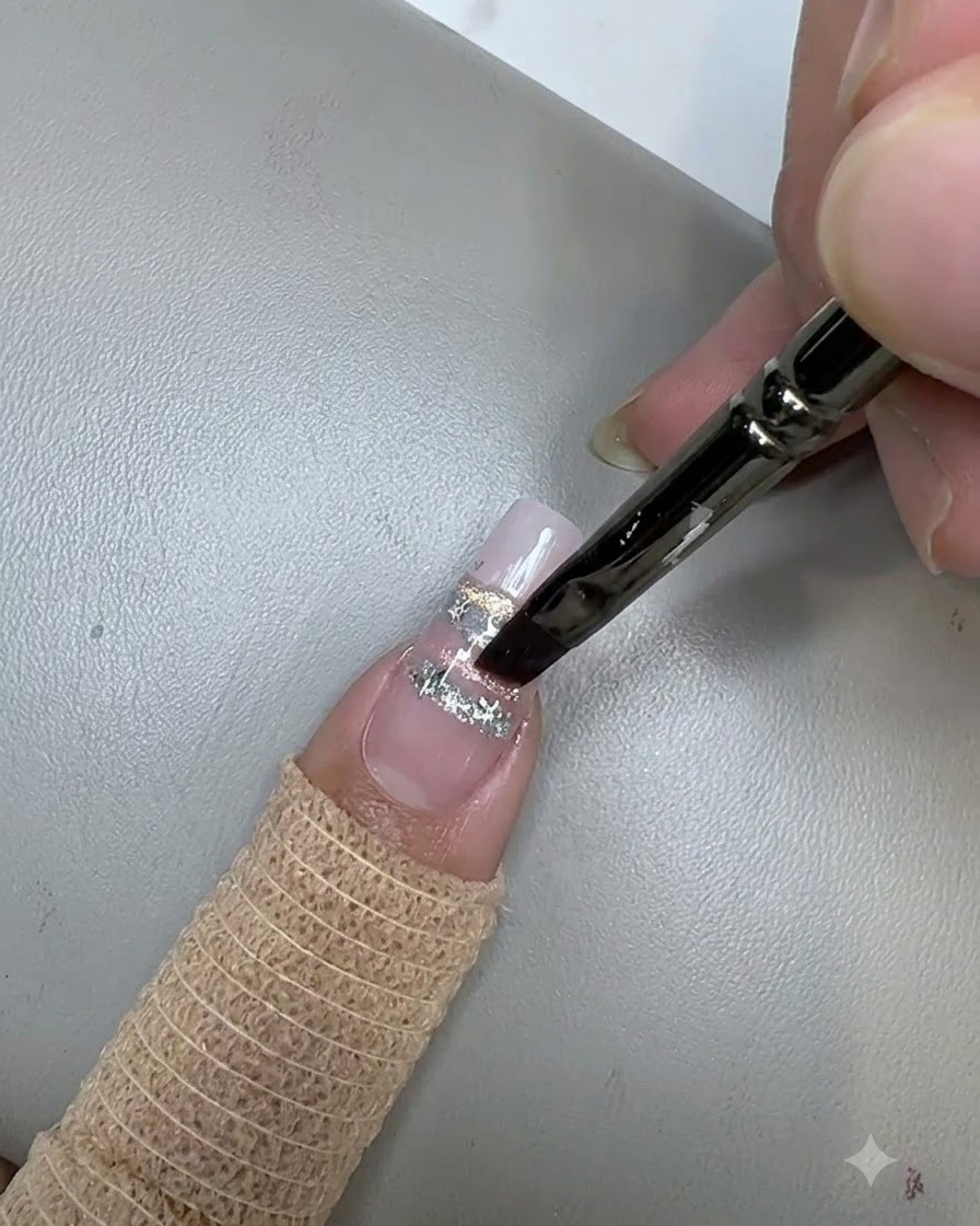 A nail brush applying a clear top coat over star sequins on a decorated nail.