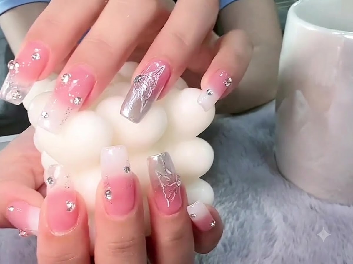 Hands holding a textured white pillar candle with focus on the 3D silver butterfly nail art.