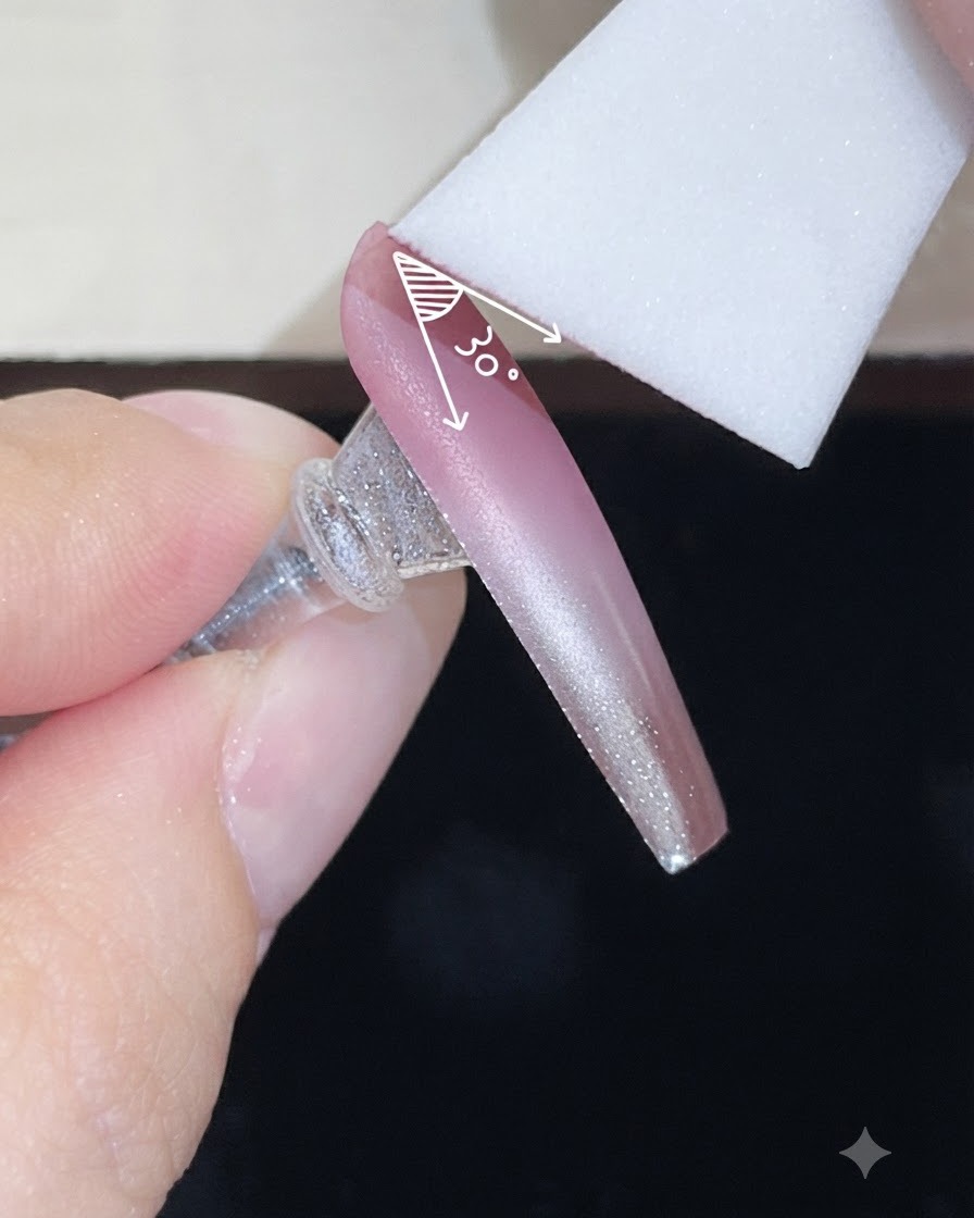 A foam sponge applying a second layer of color gel onto a nude gradient nail at a controlled angle.