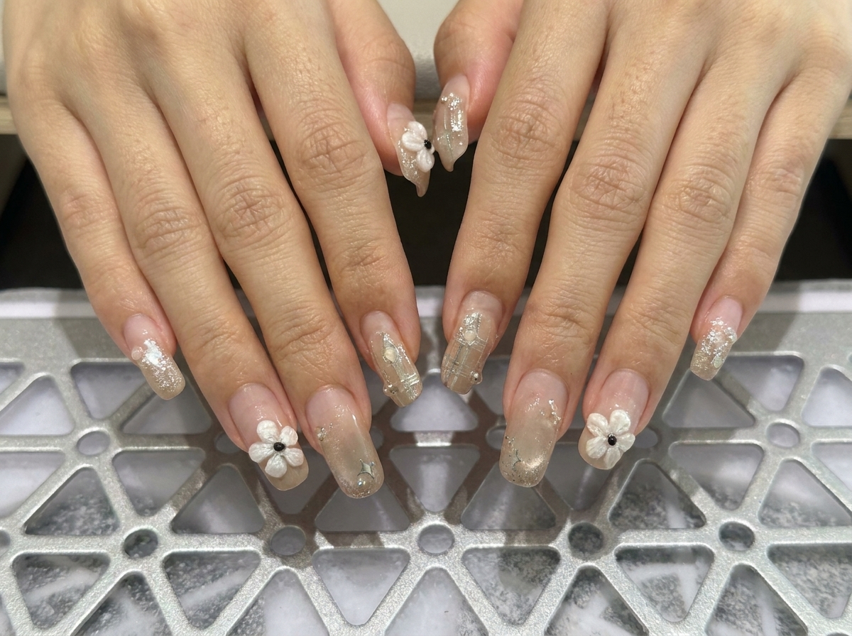 A macro shot focusing on the left hand fingers displaying structured square nails adorned with delicate pearl accents.