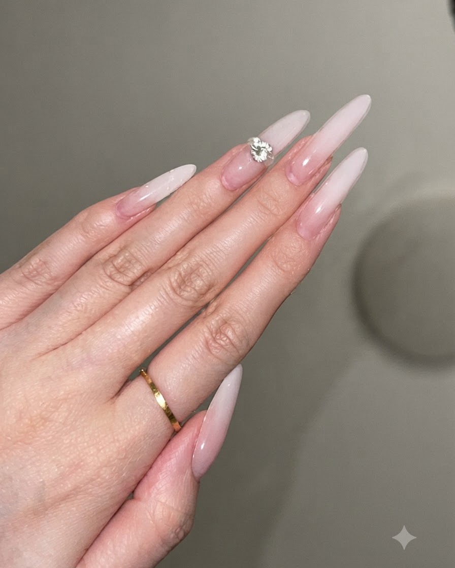 A dot of clear gel adhesive being placed on the center of a decorated stiletto nail.