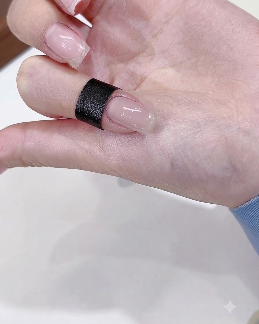 A close-up of a fingernail painted with a glossy nude gel base coat.