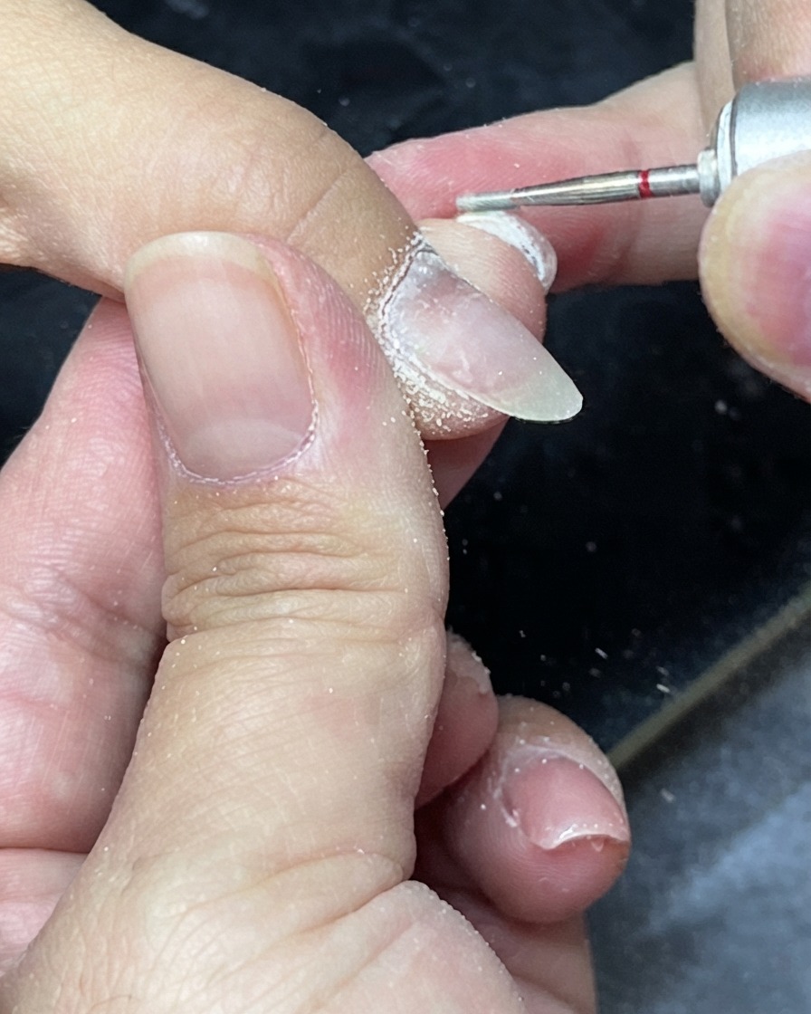 Cuticle nippers being used to trim excess dead skin around the nail folds.