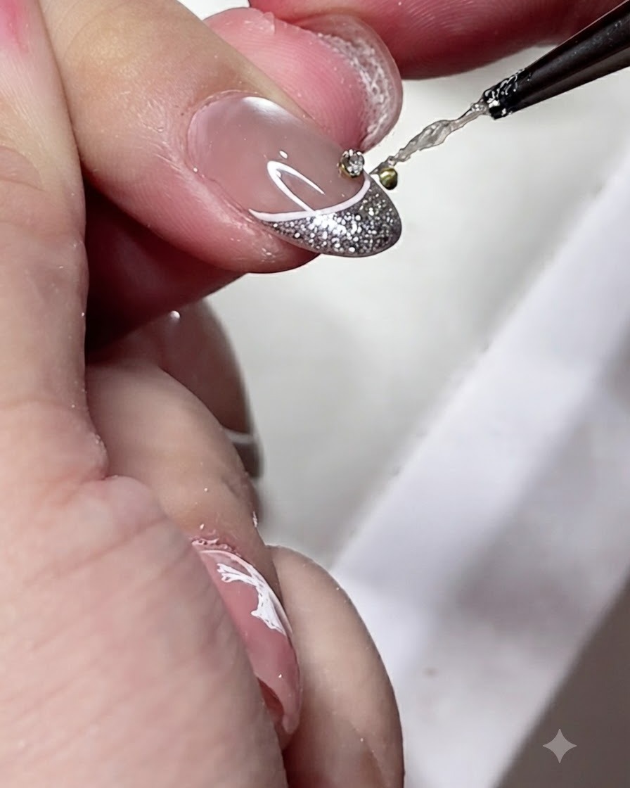 A detailing brush applying a small drop of clear gel adhesive onto the center of a decorated French manicure tip.