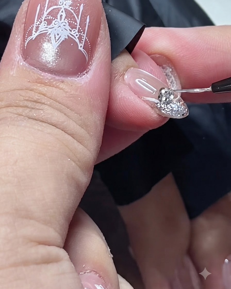 A fine detail brush applying top coat around the base of a rhinestone on a nail.