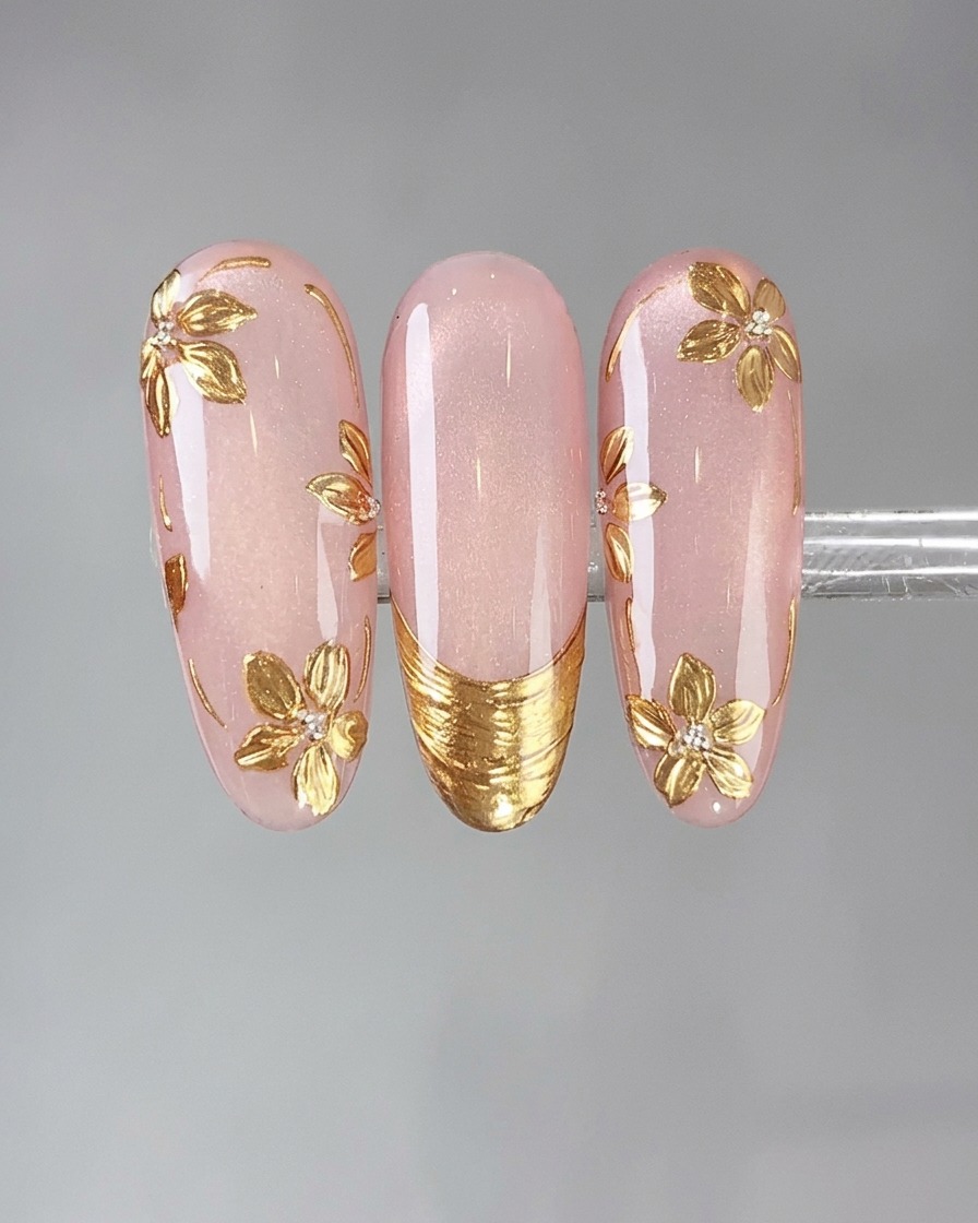 A sponge applicator pressing vintage gold mirror powder onto a detailed nail design.