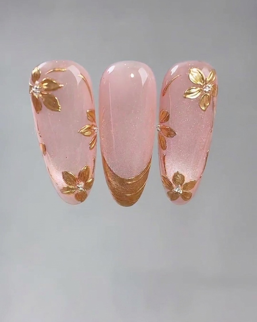 A detail shot of a fine tool placing a small dot of sticky nail glue onto a pink cat-eye gel nail.