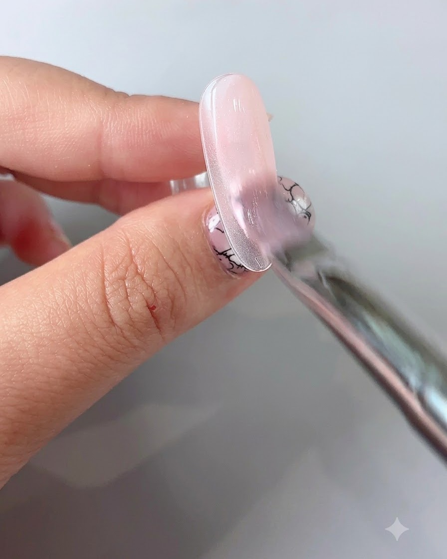 A fine liner brush drawing delicate thin lines on a gel-polished nail.