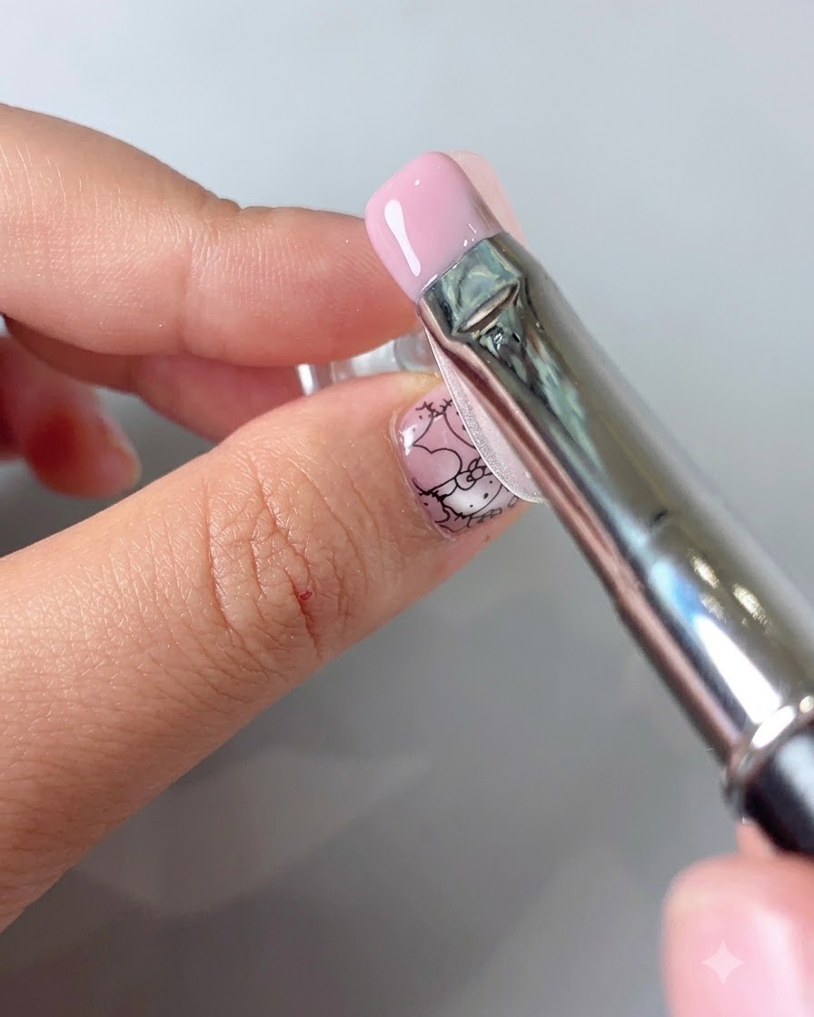 A fine-tipped tool placing tiny metallic beads into the center of a gold flower.