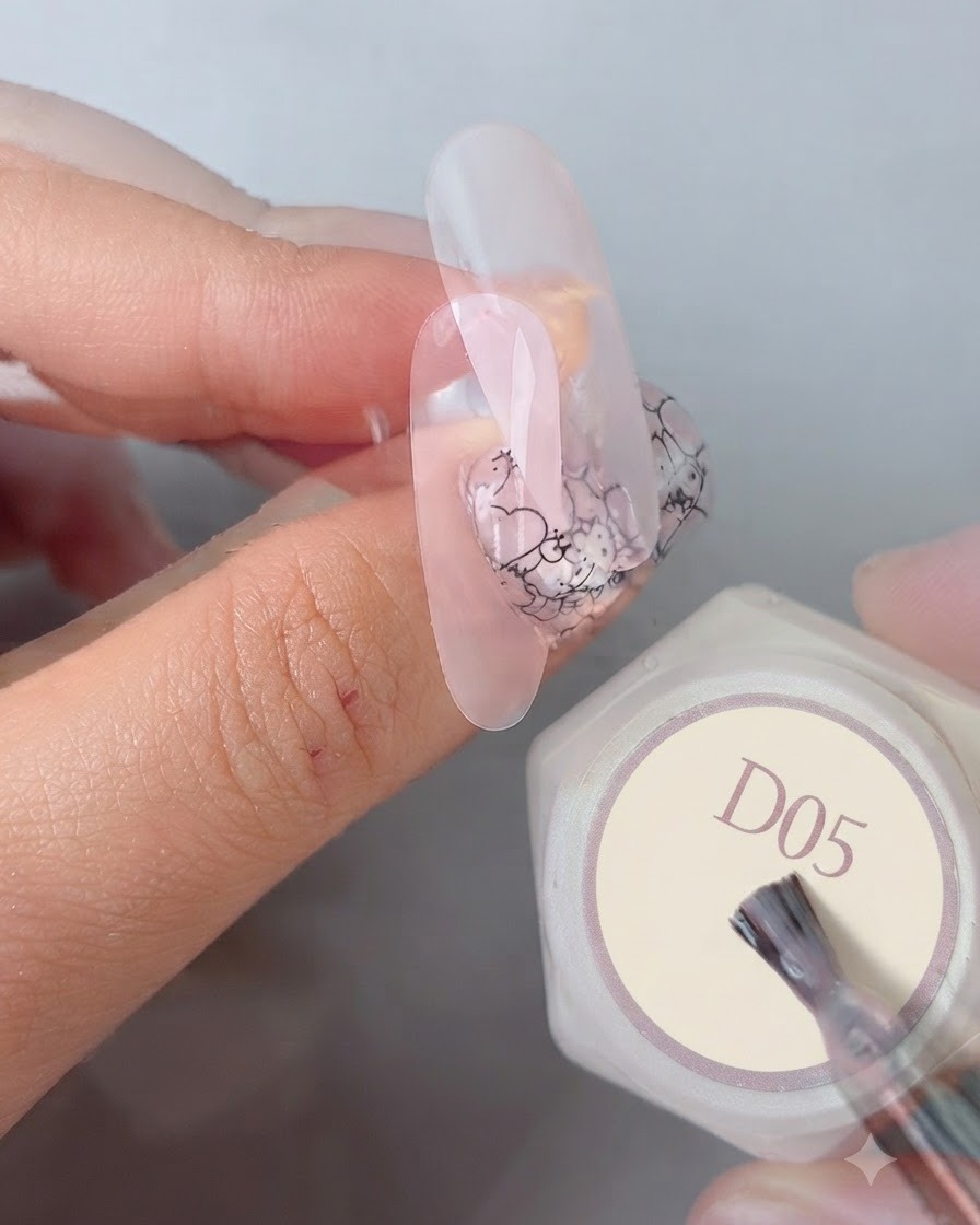 A manicure brush applying a final glossy smooth top coat over a completed nail design next to a gel bottle labeled D05.