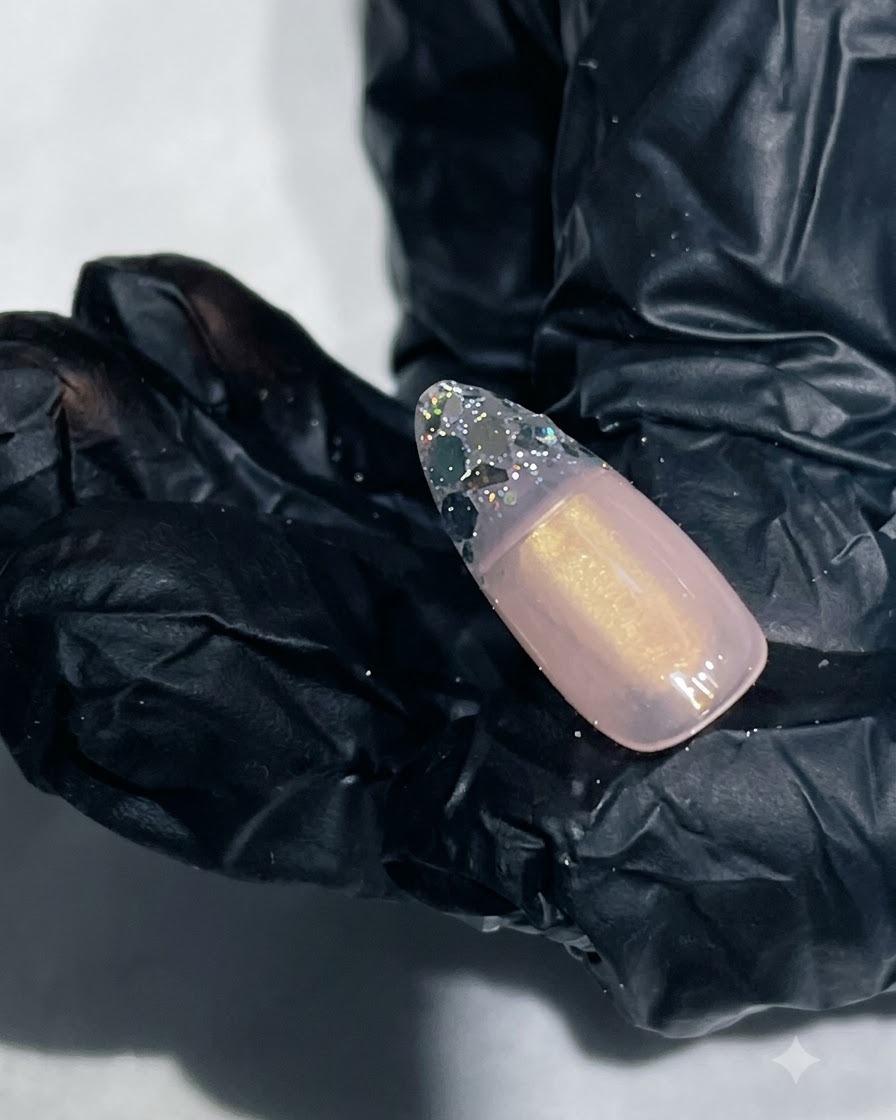 A close-up of a nail with smooth reinforcing gel encapsulating the glitter tip.