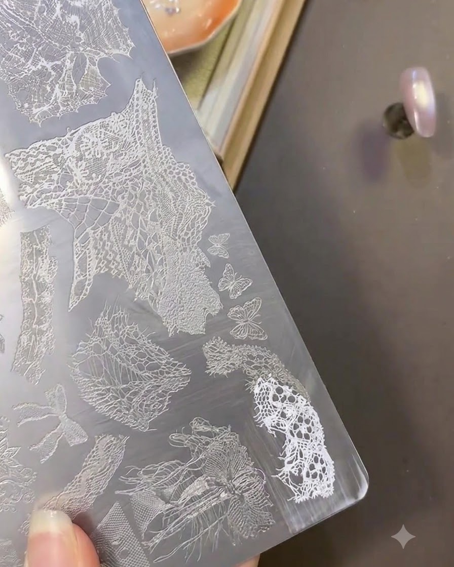 A clear silicone stamper head showing a picked-up white lace pattern.