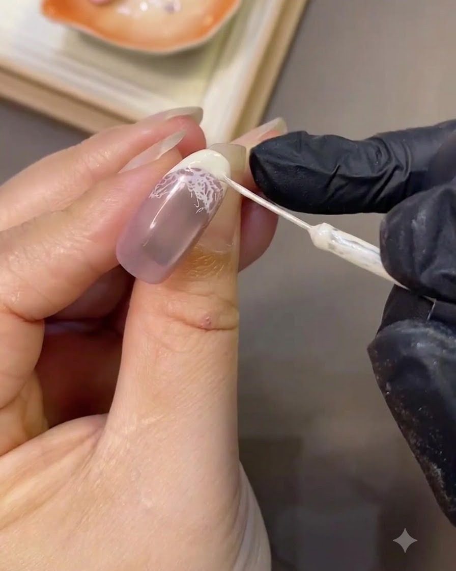 A fine liner brush precision-refining the crisp white curve of a French tip on a manicured nail.