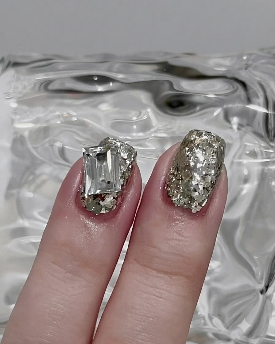 A nail brush smoothing out silver glitter into a thin, even layer across the nail.