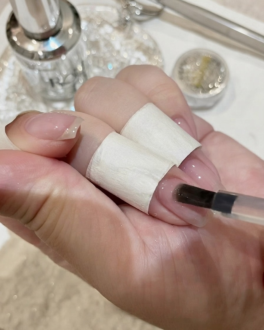 Nails with a large crystal gemstone curing under a UV lamp.