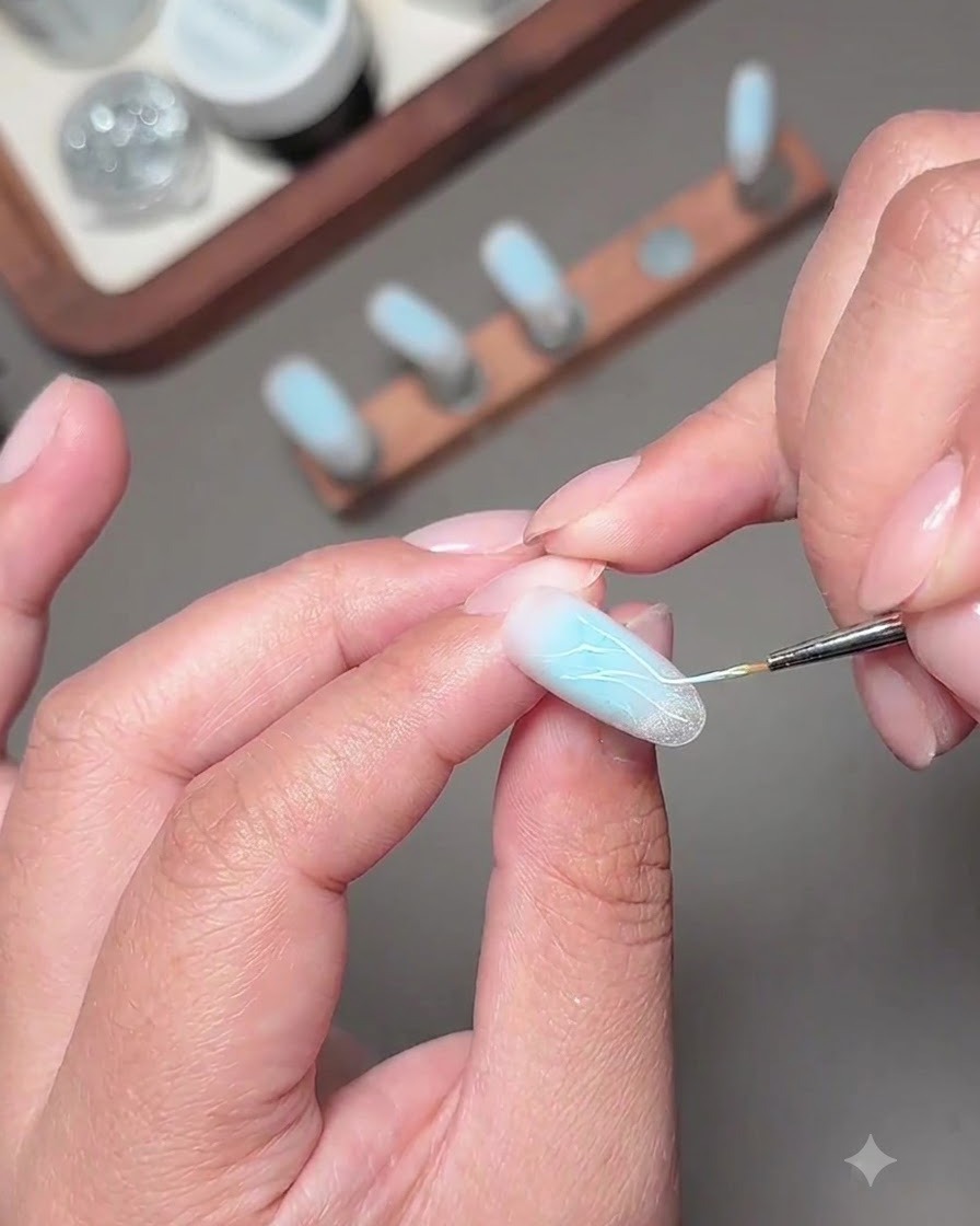 A fine brush applying sparkly fragment diamond gel lines onto the decorated nail.