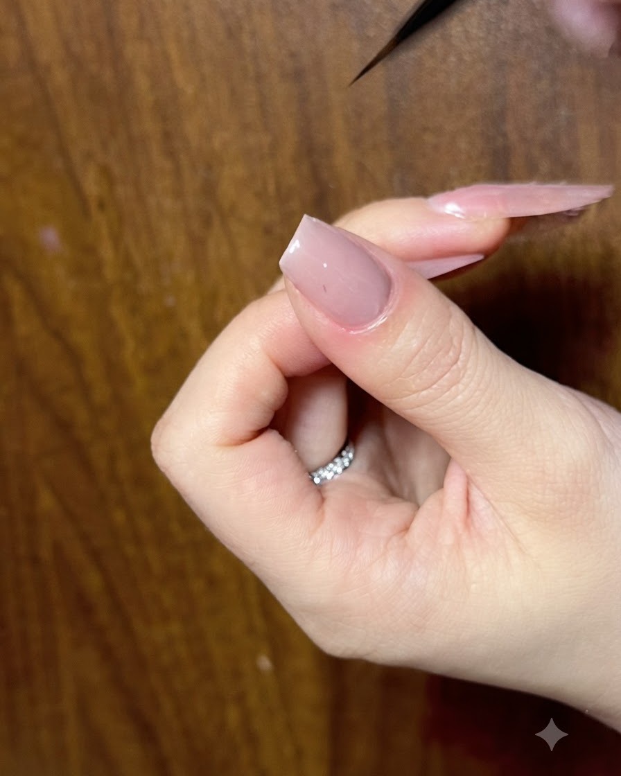 A close-up of a nail being refined with a fine liner brush to ensure clean bow contours.