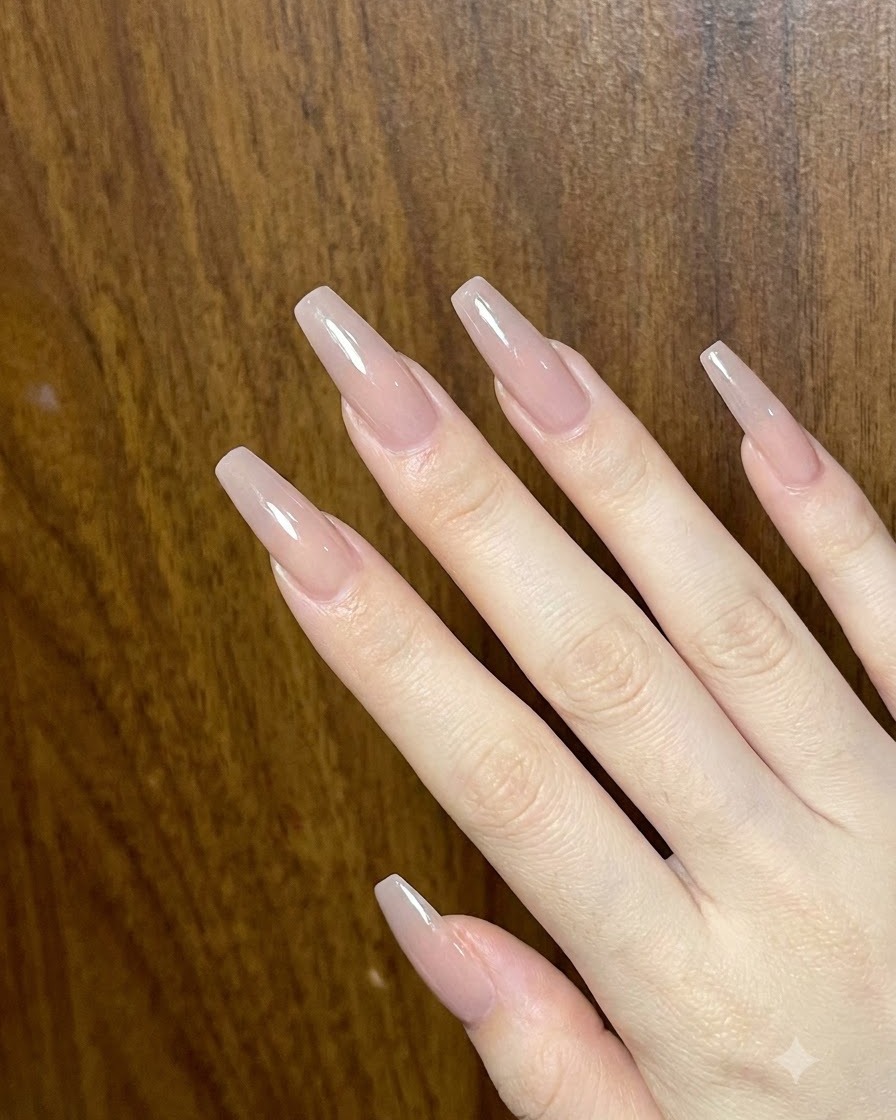 An overview of a hand displaying multiple long, glossy nude-toned acrylic nails.