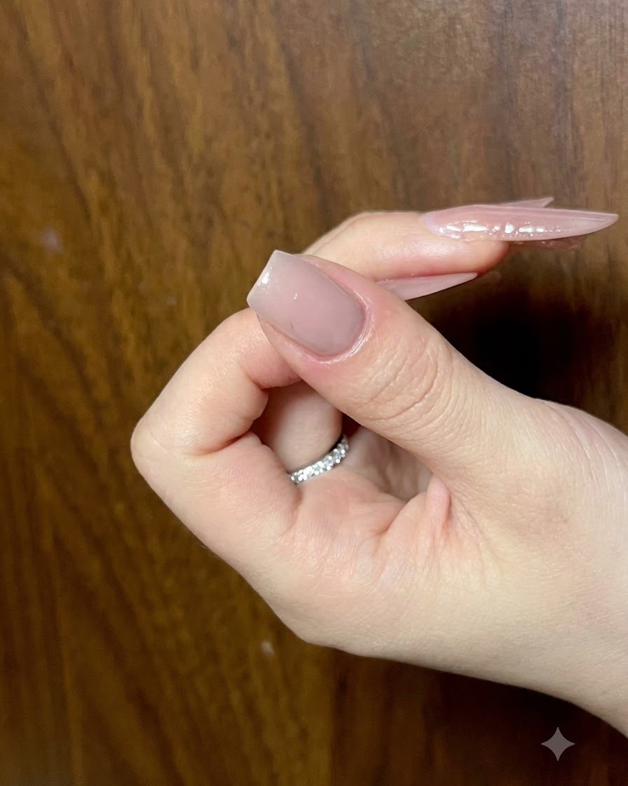 A close-up of a nude manicured nail receiving detailed cat-eye gel strokes for butterfly wing art.