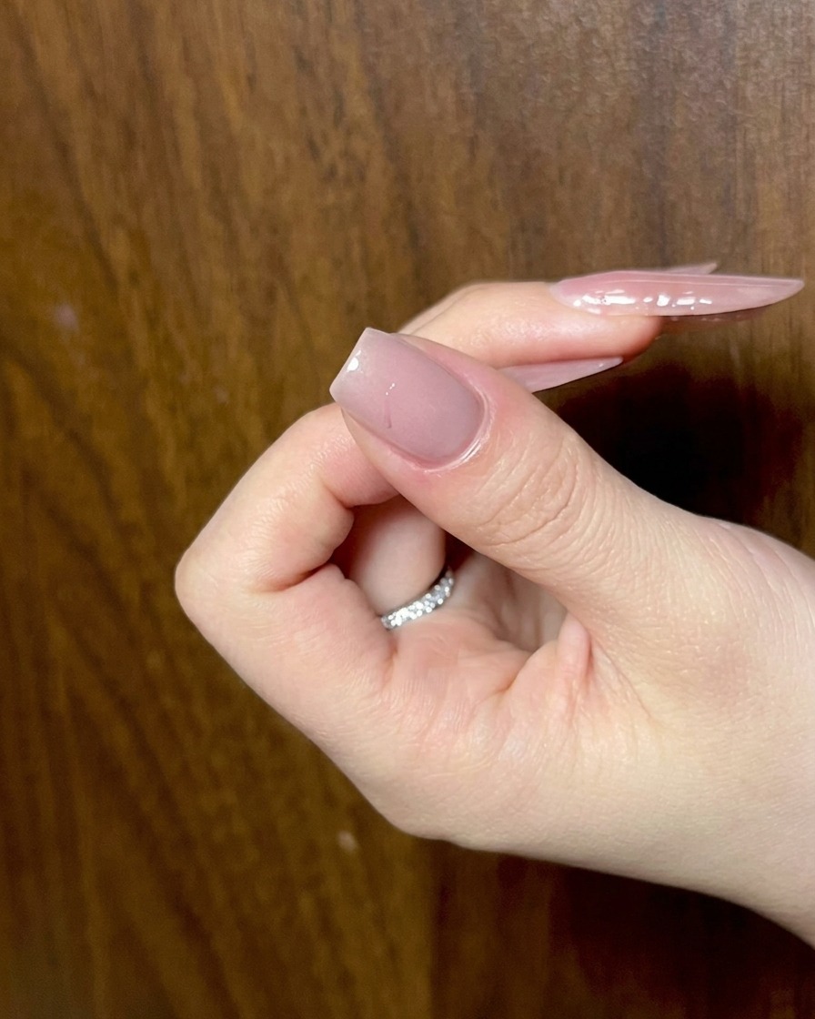 A close-up shot of black gel being used to trace the wing shapes of a bow design on a fingernail.
