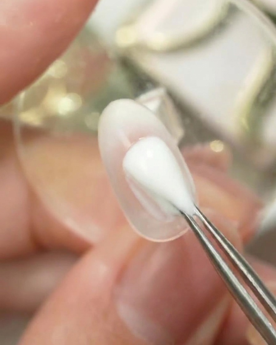 A tool dabbing Gulauri palette color number 6 onto a clear nail surface to create an ombre gradient.
