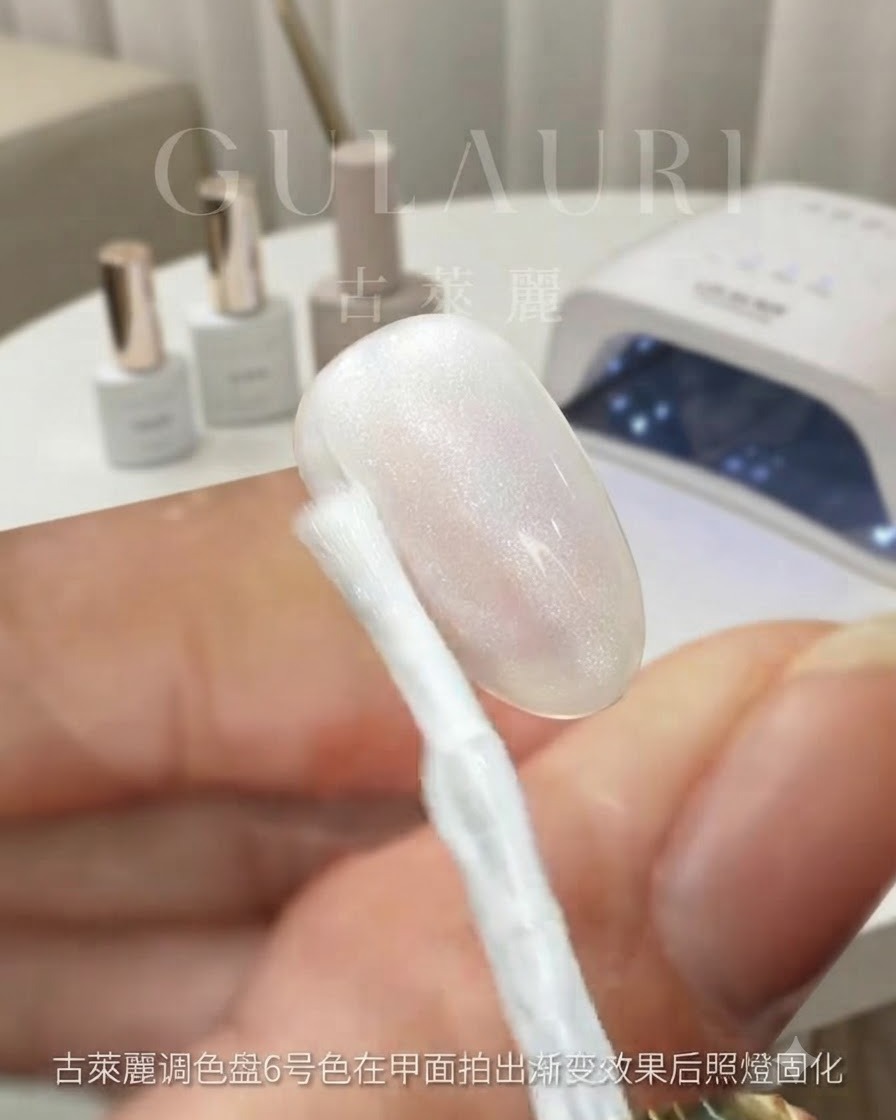 A brush applying Traveler color number 1 over the ombre nail surface, showing a glossy shimmering coat.