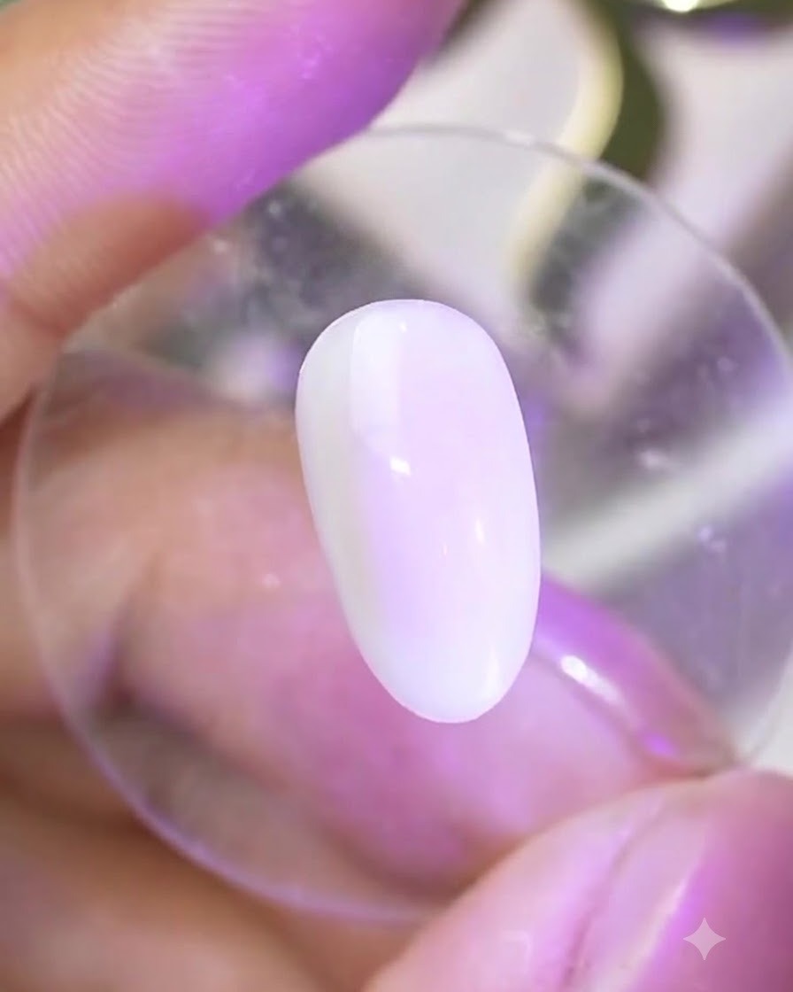 A cured nail surface under a lamp reflecting a smooth, glossy finish ready for powder application.