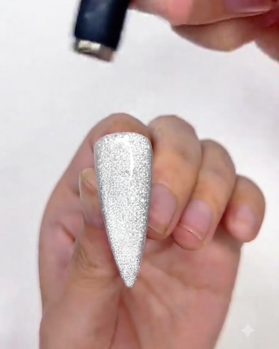 A magnet adjusting the upper portion of the cat-eye gel polish on the nail.