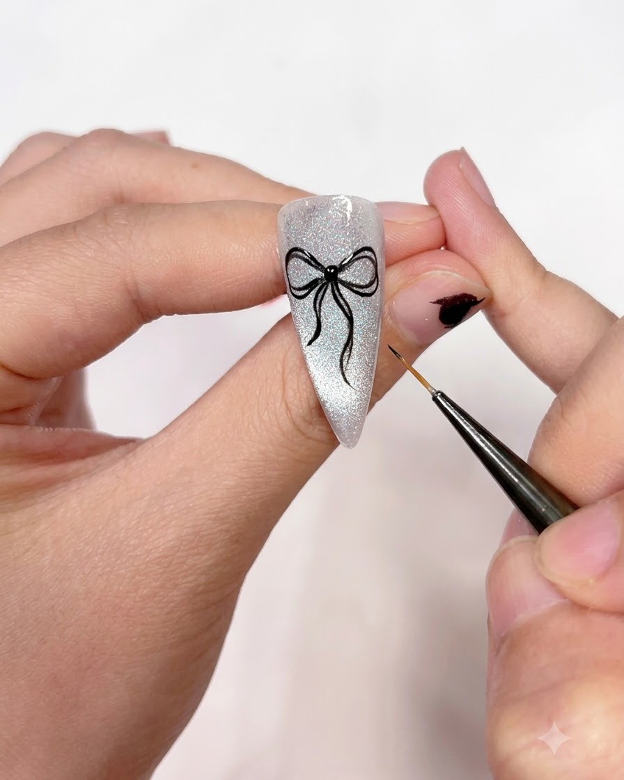 A close-up shot showing a fine liner brush tracing over the black bow outlines to make them crisp, opaque, and even.