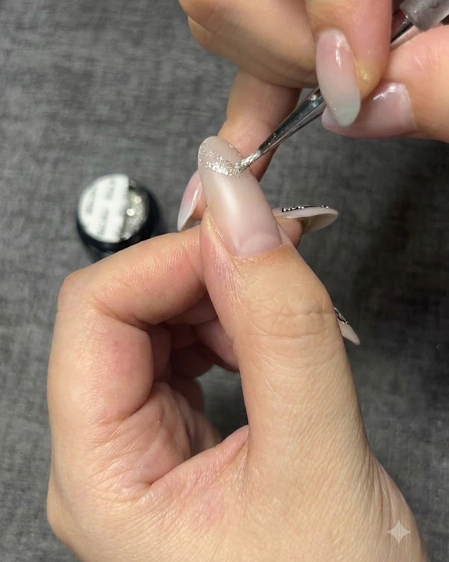 A fine detail brush applying sparkling silver gel to create a butterfly outline on a nail.
