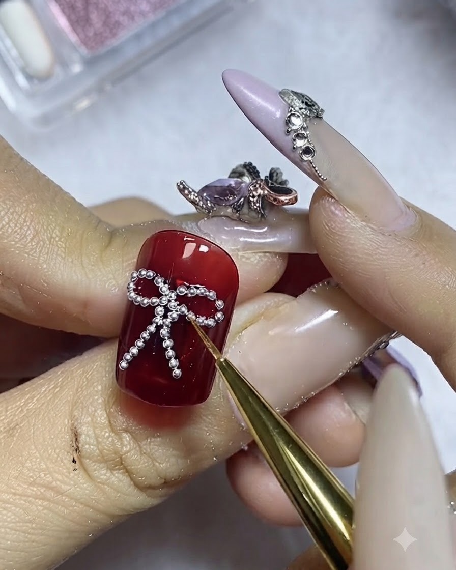 A fine brush applying top coat carefully around the perimeter of silver steel beads on a red nail.
