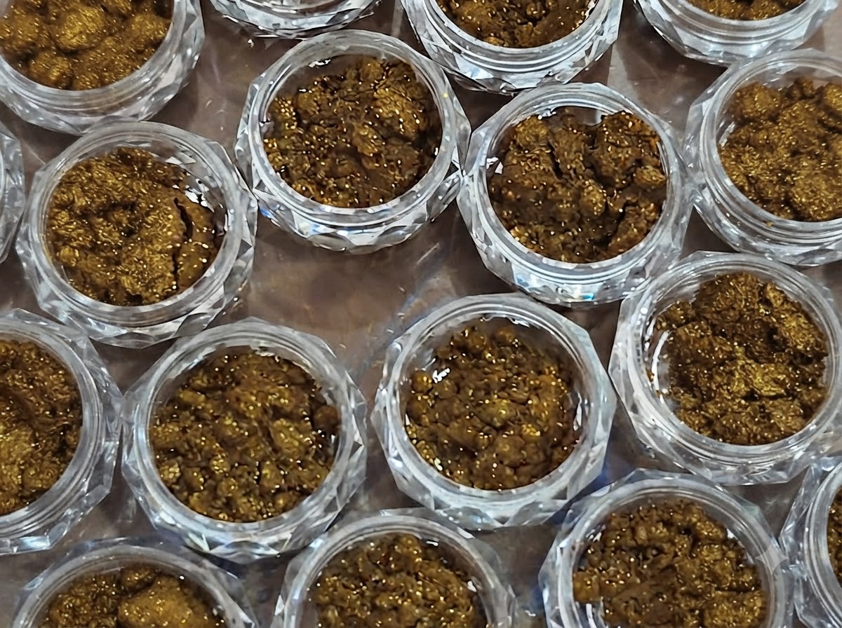 A close-up view of multiple small jars completely filled with textured bronze mirror powder.