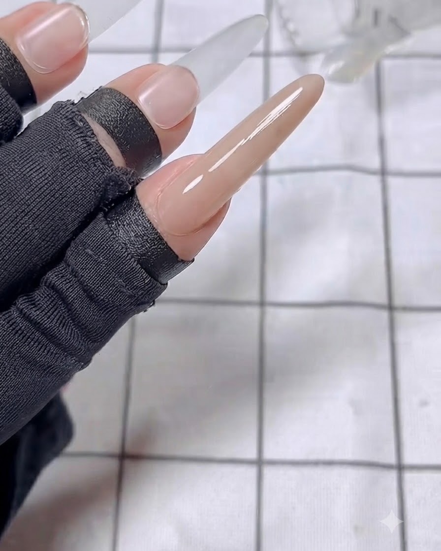A close-up view of the index finger showing a glossy top coat layer applied over the nude base.