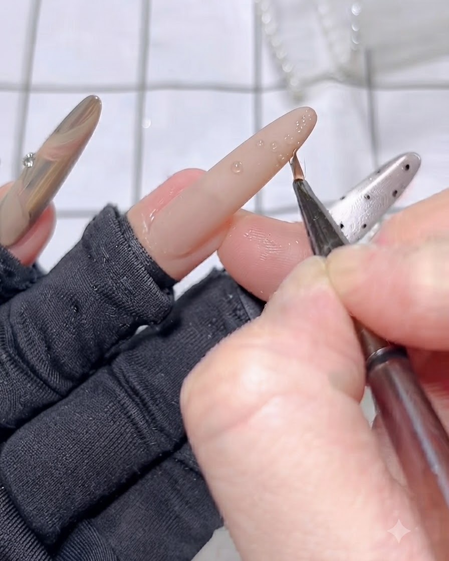A fine brush creating raised 3D gel line patterns on the tip of the ring finger.