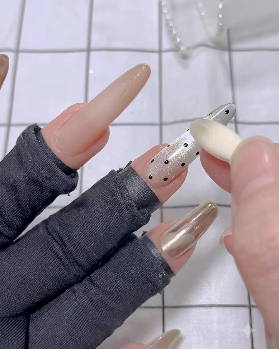An applicator sponge buffing golden mirror powder onto the textured 3D lines of a finished nail.