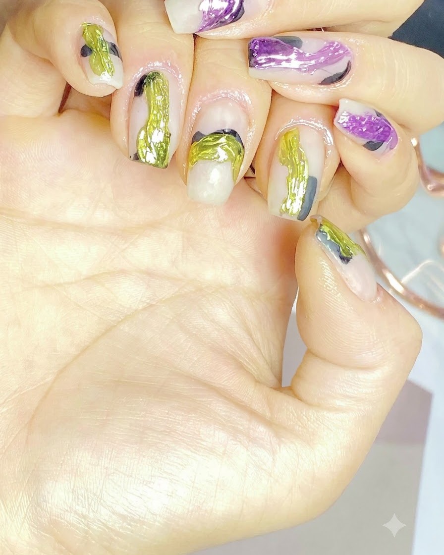 A nail brush applying a clear base coat onto a natural fingernail.