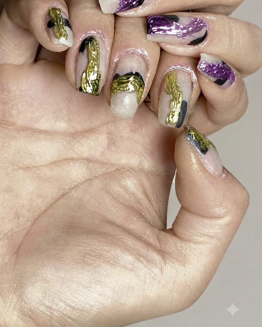 A brush applying a clear gloss top coat over finished abstract nail art.